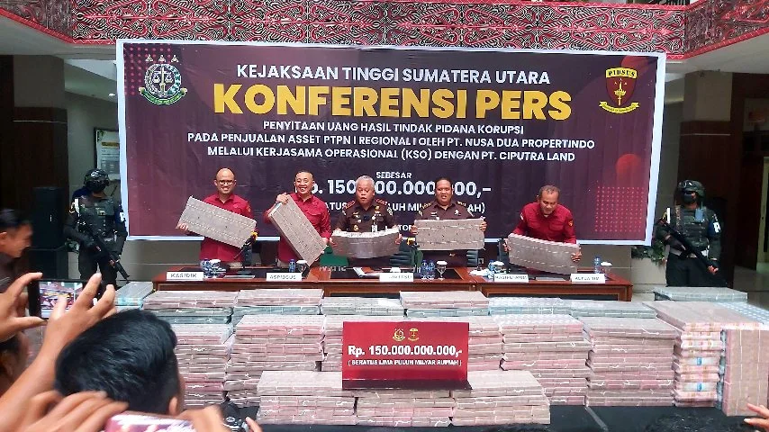Lima pria di depan spanduk konferensi pers Kejaksaan Tinggi Sumatera Utara terkait penyitaan uang hasil tindak pidana korupsi dari penjualan aset PTPN I melalui kerjasama operasional dengan PT. Nusa Dua Properindo dan PT. Ciputra Land. Di depan mereka terhampar tumpukan uang tunai yang disita senilai Rp 150.000.000.000,- (seratus lima puluh miliar rupiah).
