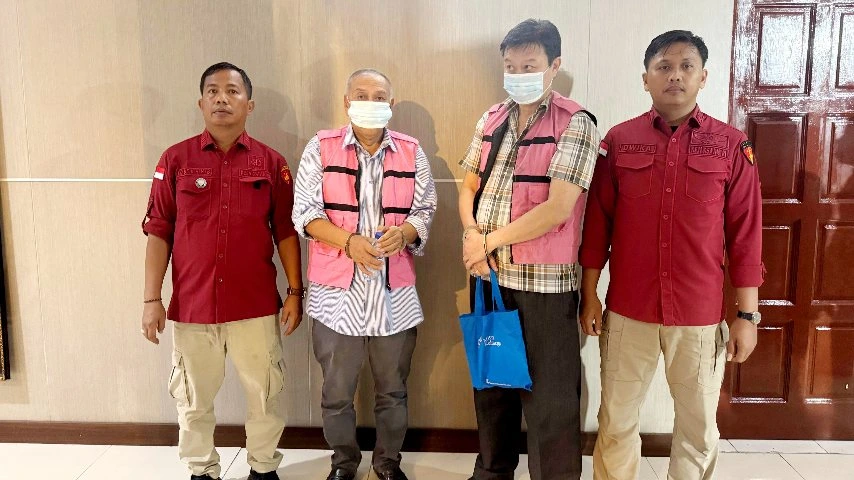 Dua tersangka kasus dugaan korupsi pengadaan smartboard Tebing Tinggi mengenakan rompi tahanan warna merah muda dan diborgol, berdiri diapit dua petugas Kejaksaan Tinggi Sumatera Utara.