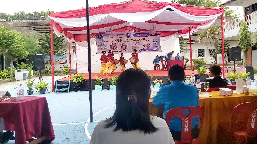 Para siswa menampilkan tarian tradisional di atas panggung merah putih, disaksikan para juri yang duduk di meja penilaian pada lomba seni jubileum 100 tahun Perguruan Nasrani Medan.