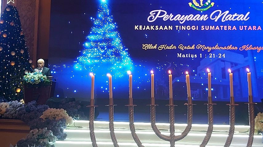 Suasana ibadah Perayaan Natal Kejaksaan Tinggi Sumatera Utara 2025 di Regale International Convention Center Medan dengan lilin Natal dan dekorasi panggung.