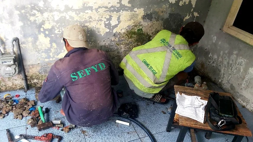 Petugas PDAM Tirtanadi Sei Agul memperbaiki kebocoran pipa di sambungan meteran air warga di Jalan Sakura 2, Helvetia Perumnas Helvetia Medan.