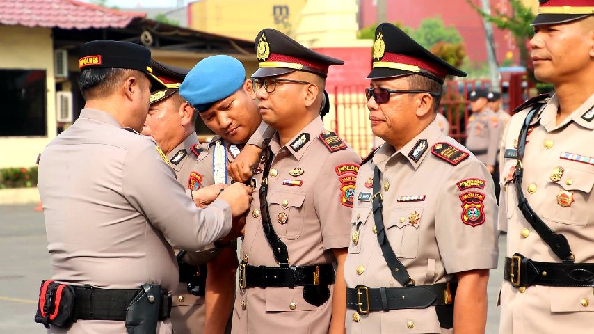 Seorang pejabat kepolisian menyematkan tanda jabatan kepada anggota saat upacara serah terima jabatan di lingkungan Polres.